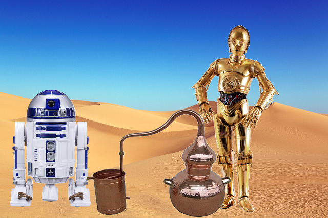 Na pustyni stoją dwa roboty z filmu Gwiezdne Wojny a pomiędzy nimi aparat do destylowania alkoholu