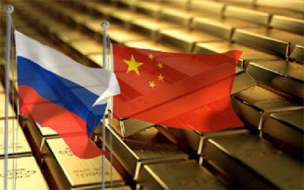 Flagi Rosji i Chin na tle sztabek złota